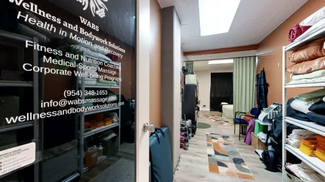 Office 227 entry passage with lettering on the glass door, linen shelves, patterned rugs and a curtained treatment area.