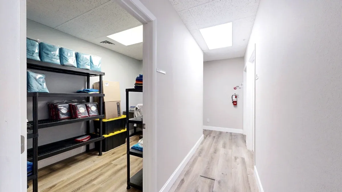 Open doorway into Office 217 shows black storage shelves and stacked bins beside a light-colored hallway.
