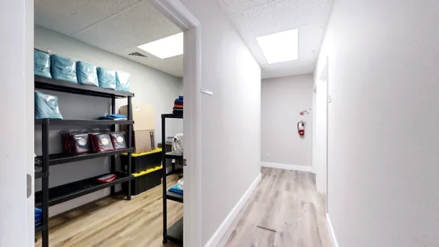 Open doorway into Office 217 shows black storage shelves and stacked bins beside a light-colored hallway.