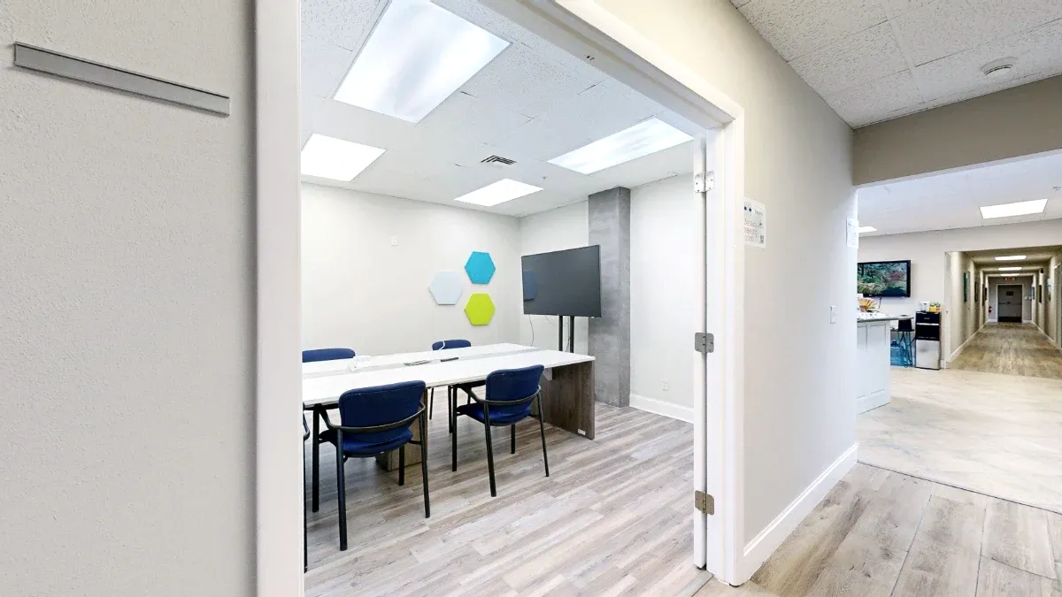 View through The Canaveral's entrance toward white tables, blue chairs and a display, with reception visible to the right.