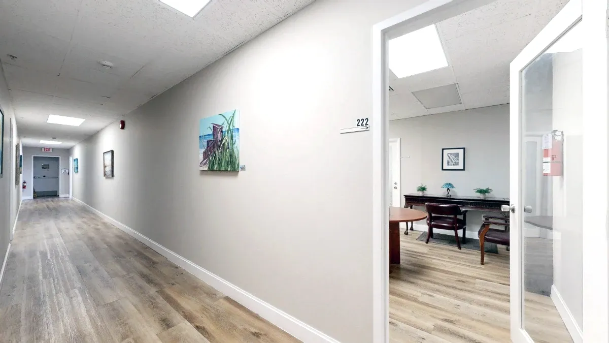 Main hallway with wall art and an open glass door into the Suite 222 shared seating area.