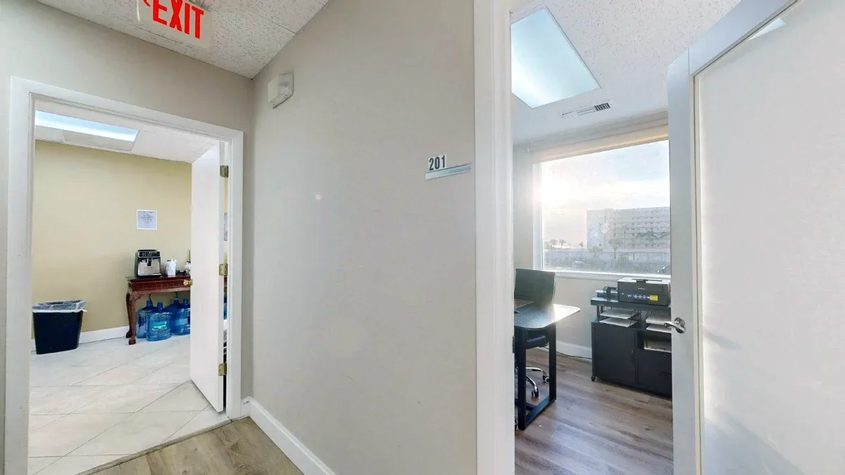 Hallway view of the open Office 201 doorway on the right and the adjacent kitchen doorway on the left.