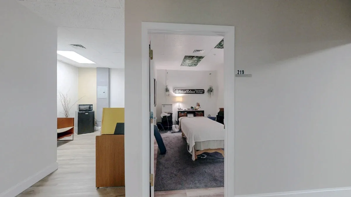 Open doorway marked 219 reveals a massage table, with seating and a small refrigerator in the adjacent connecting area.